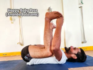 A person lying on their back, holding their feet in Happy Baby Pose (Ananda Balasana) yoga position.