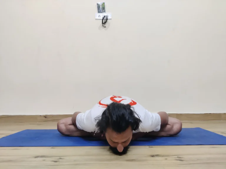 A person practicing Baddha Konasana A, or Bound Angle Pose, in yoga with the soles of the feet together and knees apart.