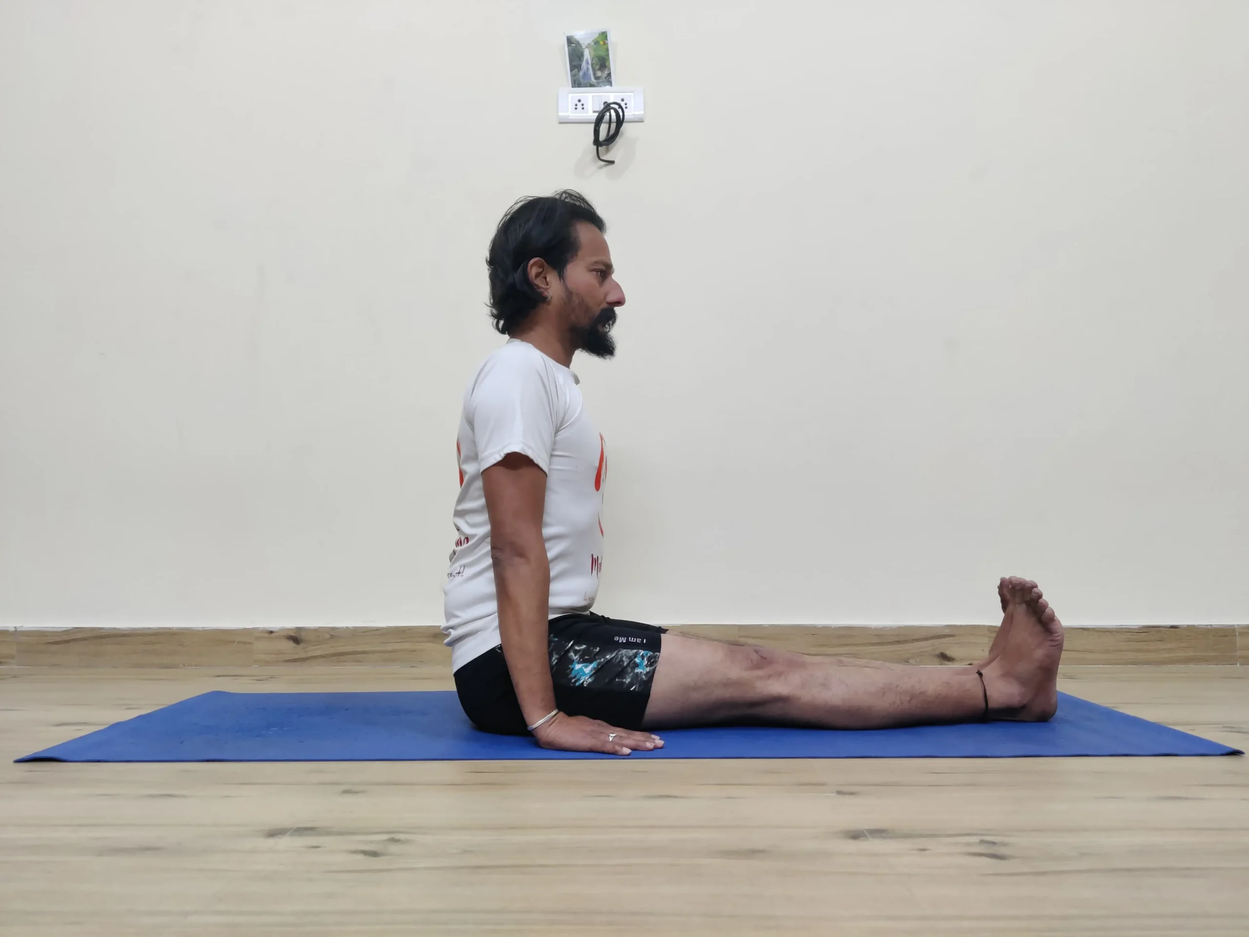 A man performing Dandasana, also known as Staff Pose, in yoga.