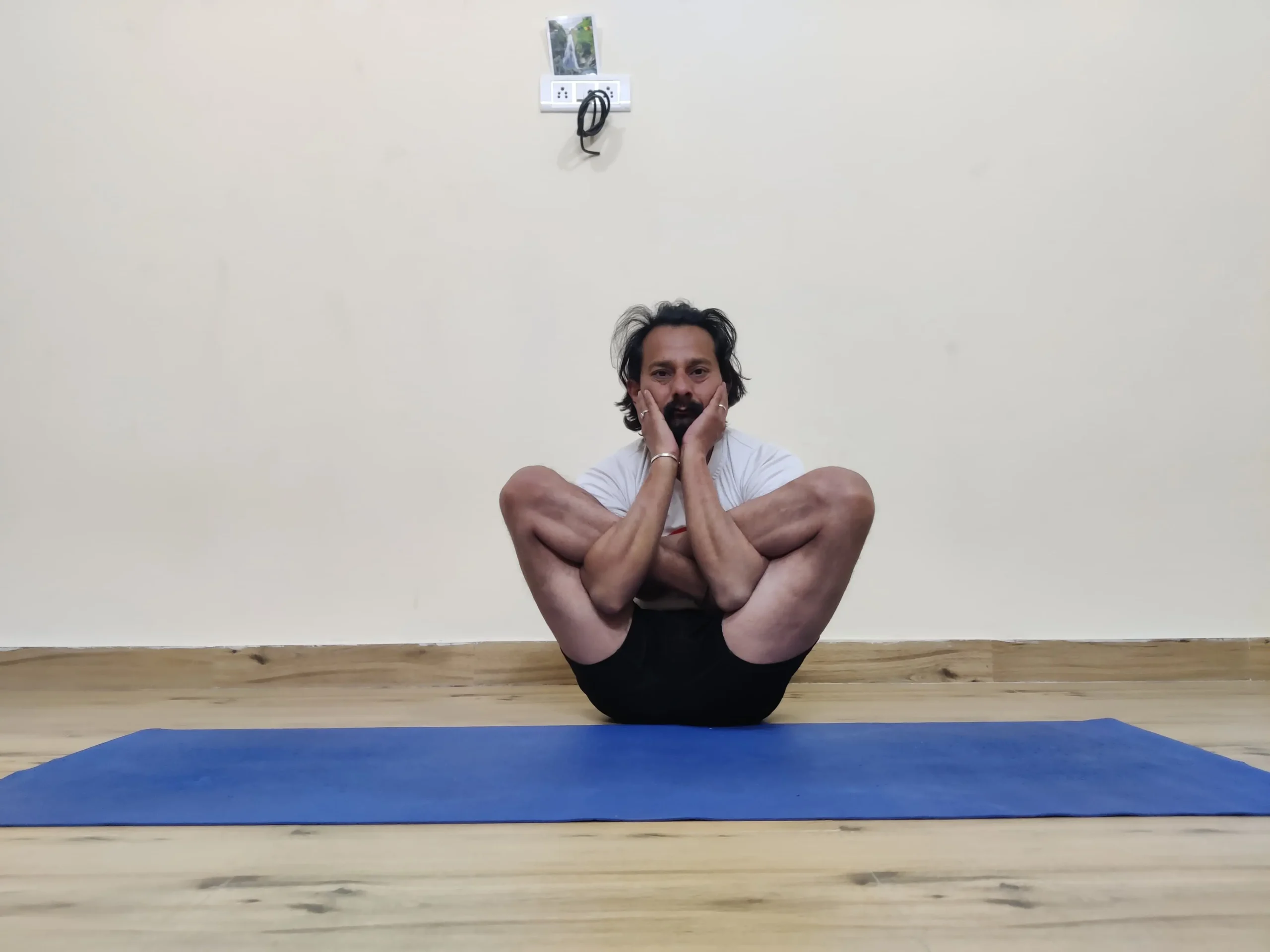 A person practicing Garbha Pindasana, or Embryo Posture, in yoga.