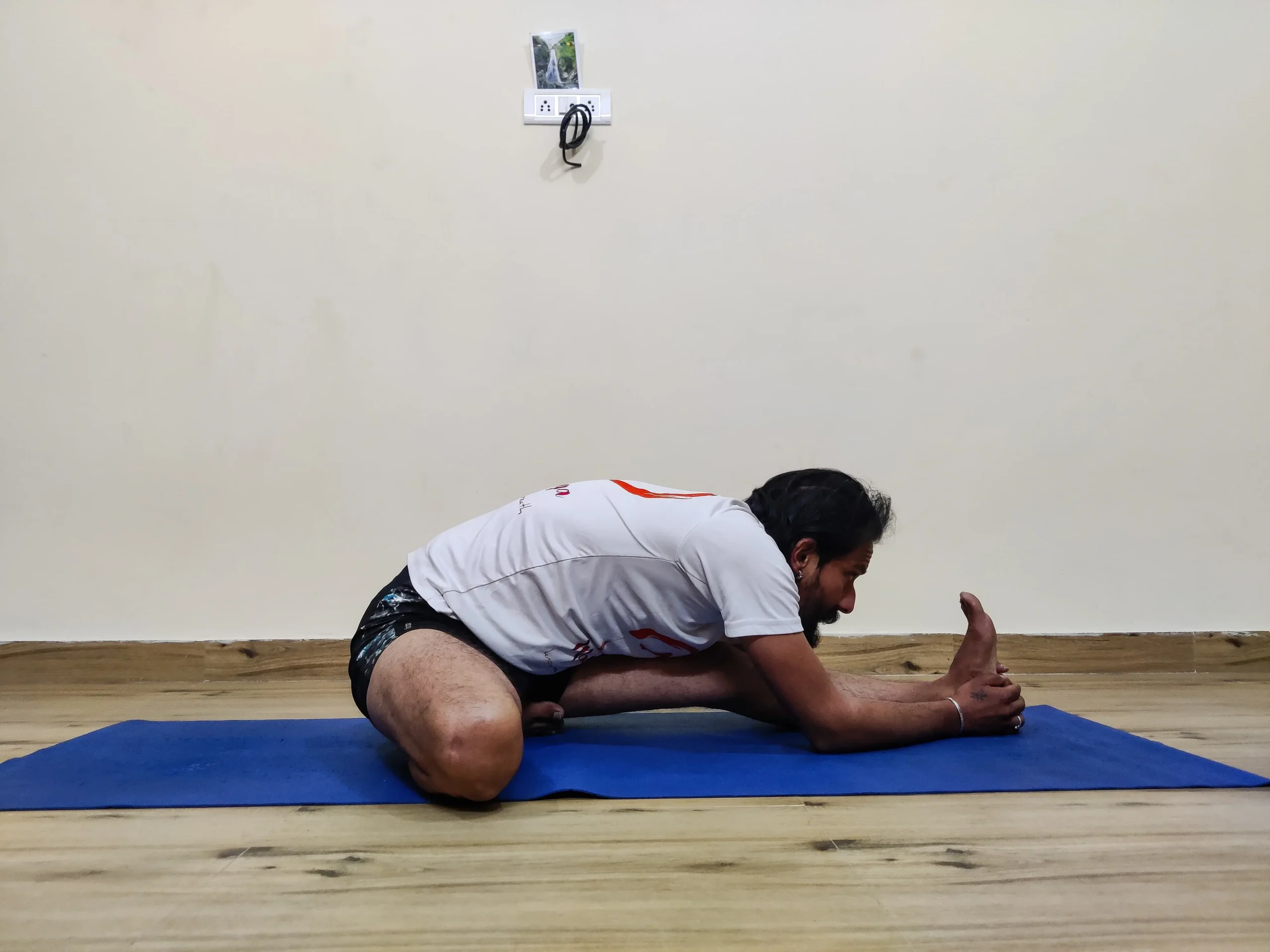 A person practicing Janu Sirsasana B, a seated yoga pose with one leg extended to the side and the other bent inward.