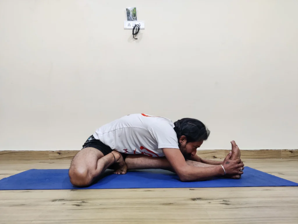 A person embodying Janu Sirsasana C, a seated yoga pose with both legs folded and feet touching.