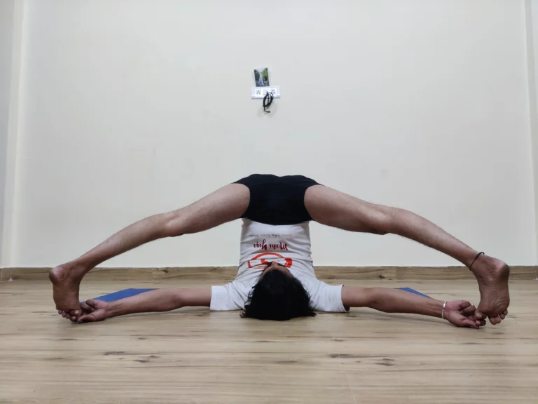 A person practicing Supta Konasana A-B, a reclined yoga pose with legs spread apart.