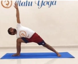 A man performing Utthita Parsvakonasana, the Extended Side Angle Posture, in a yoga studio.