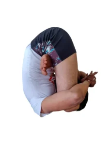 A man performing Pindasana, an embryo pose in yoga, with knees bent and hugging towards the chest.