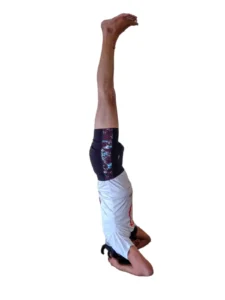 A man performing Sirsasana, a headstand pose in yoga, with the body balanced on the head and arms supporting the posture.