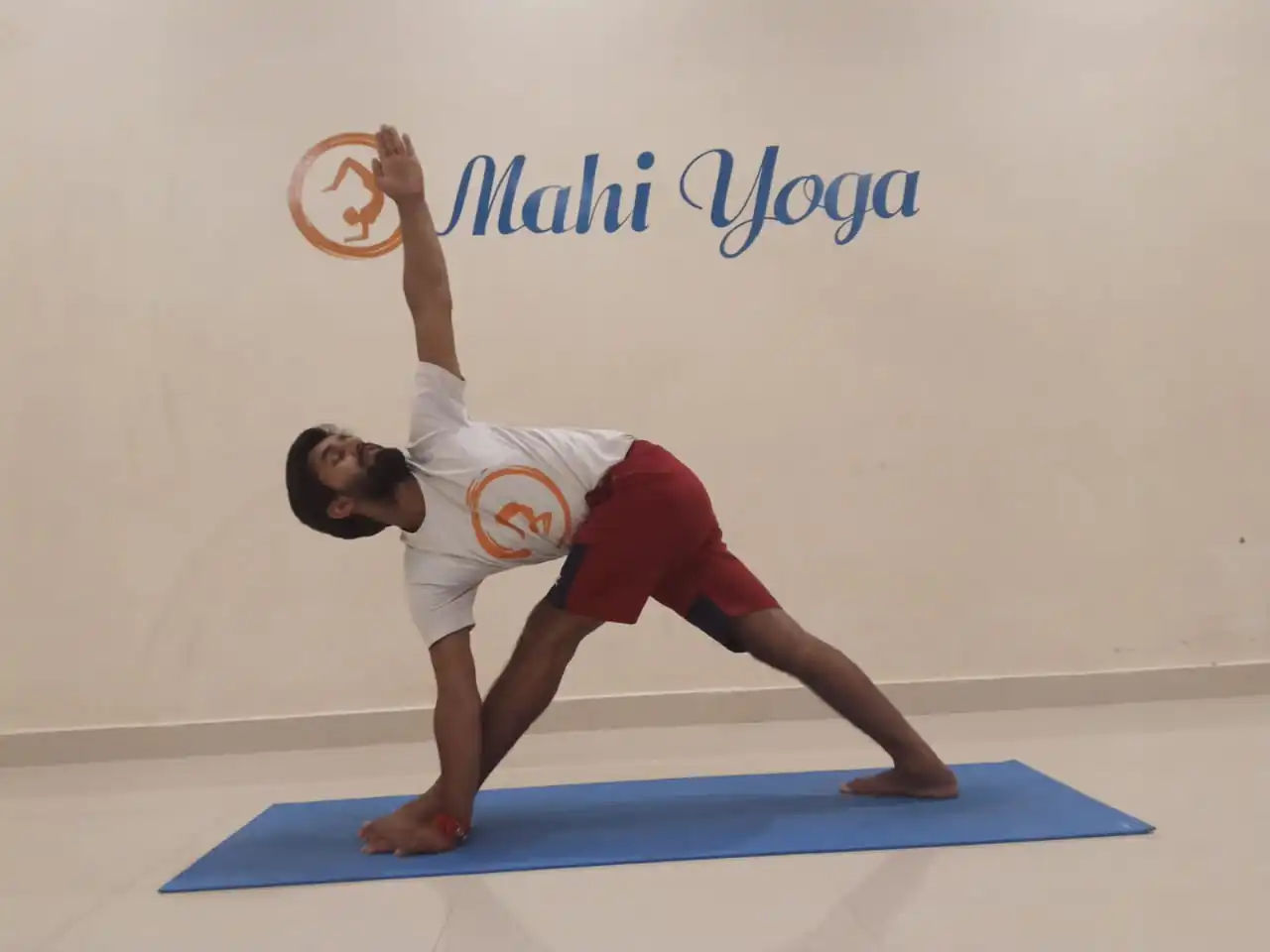 A man practicing Parivritta Parsvakonasana - Twisting Side Angle Pose during yoga session.